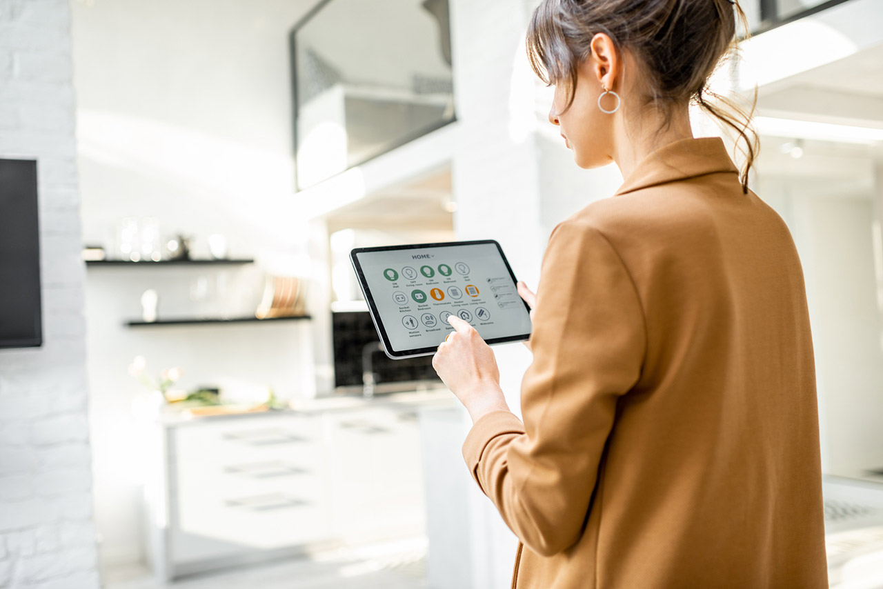 woman controlling smart home devices using a digital tablet with launched application in the white living room